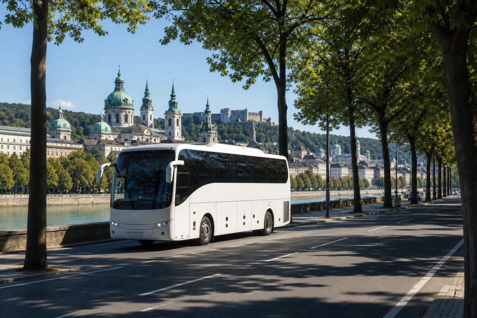 Bijeli turistički autobus na aveniji uz rijeku s povijesnim gradom u pozadini