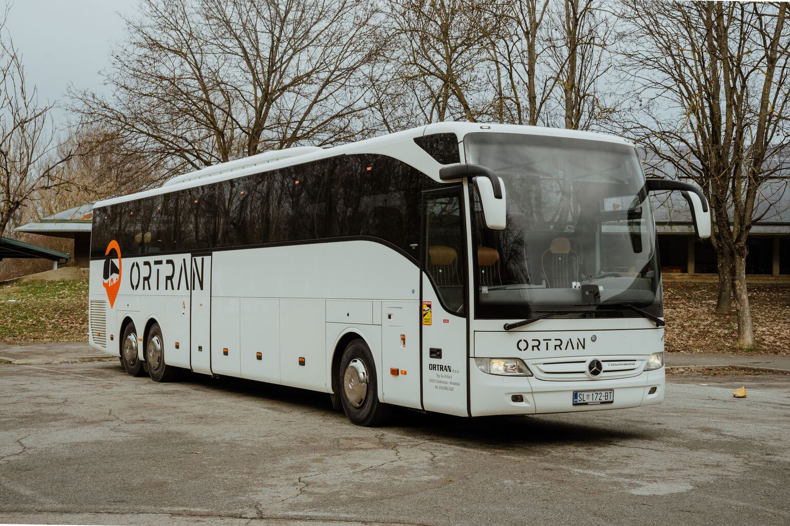 Bijeli autobus Tourismo s Ortranovim logotipom, snimljen sprijeda iz tri četvrtine na parkiralištu