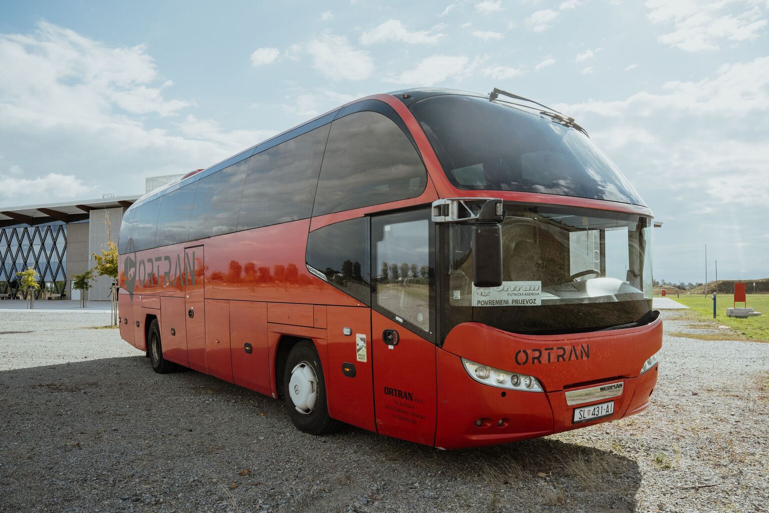 Crveni autobus Neoplan Cityliner s natpisom Ortran, snimljen sprijeda iz tri četvrtine