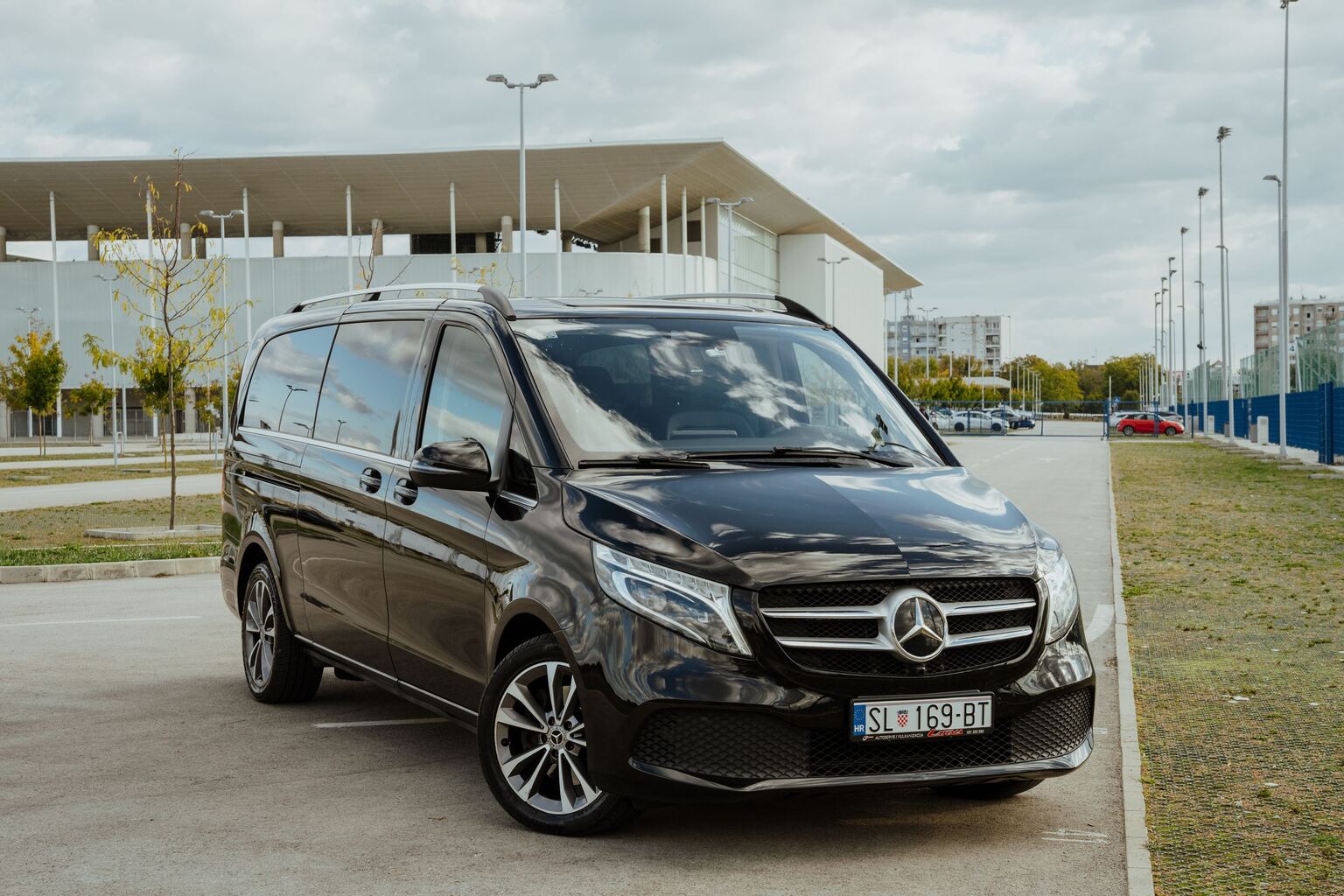 Crno vozilo Mercedes V klase snimljeno sprijeda iz tri četvrtine na parkiralištu